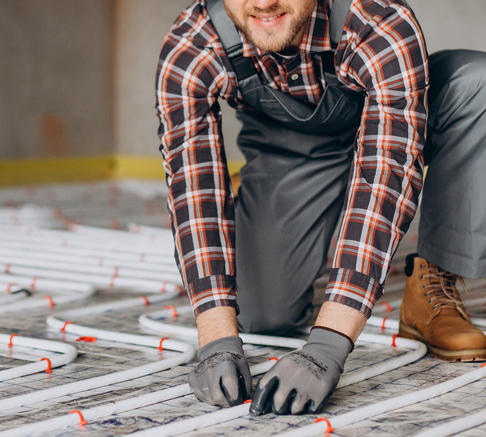Plumber at work, fitting pipes on a bathroom floor with various plumbing tools